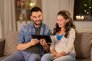 Image showing happy couple using tablet pc at home in evening