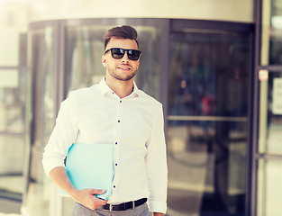 Image showing young man with business file on city street