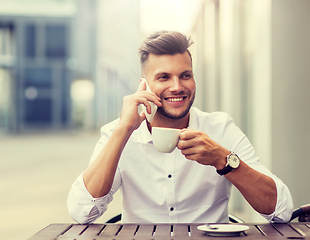 Image showing man with coffee calling on smartphone at city cafe