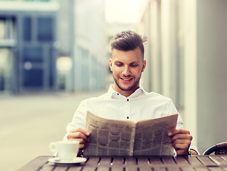 Image showing smiling man reading newspaper at city street cafe