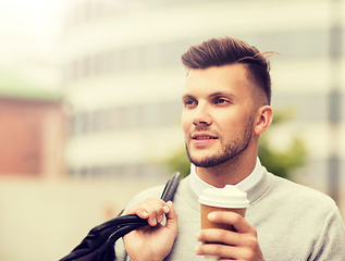 Image showing young man with bag drinking coffee in city