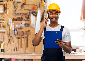 Image showing indian builder with clipboard calling on cellphone