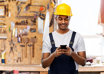 Image showing happy indian or builder in helmet using smartphone