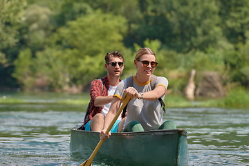 Image showing friends are canoeing in a wild river