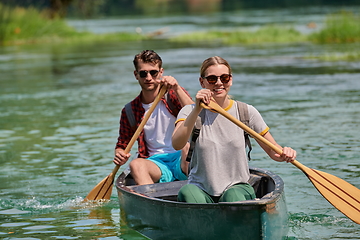 Image showing friends are canoeing in a wild river