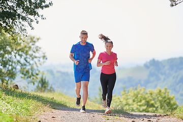 Image showing couple enjoying in a healthy lifestyle while jogging on a country road