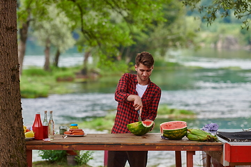 Image showing man cutting juicy watermelon during outdoor french dinner party