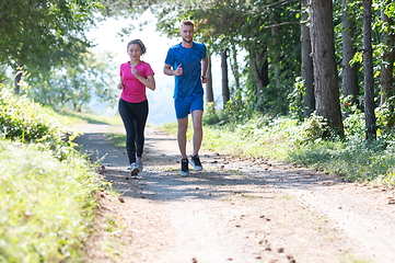 Image showing couple enjoying in a healthy lifestyle while jogging on a country road