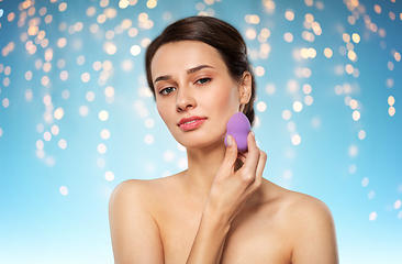 Image showing young woman with sponge applying makeup