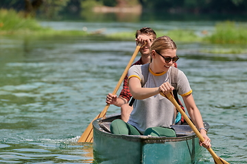 Image showing friends are canoeing in a wild river