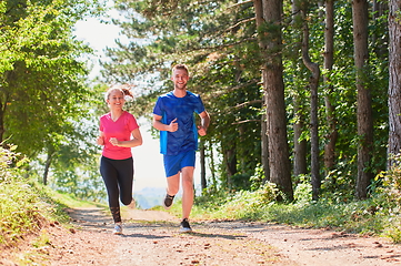 Image showing couple enjoying in a healthy lifestyle while jogging on a country road