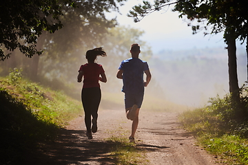 Image showing couple enjoying in a healthy lifestyle while jogging on a country road