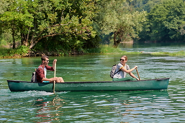 Image showing friends are canoeing in a wild river