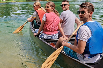 Image showing Group adventurous explorer friends are canoeing in a wild river