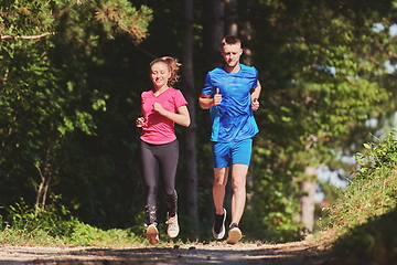 Image showing couple enjoying in a healthy lifestyle while jogging on a country road