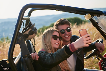 Image showing couple enjoying beautiful sunny day taking selfie picture while driving a off road buggy