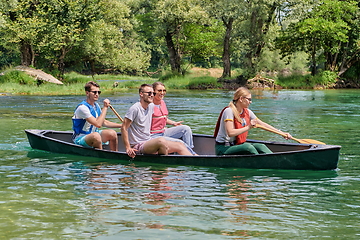 Image showing Group adventurous explorer friends are canoeing in a wild river