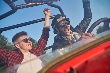 Image showing two young happy excited men enjoying beautiful sunny day while driving a off road buggy car