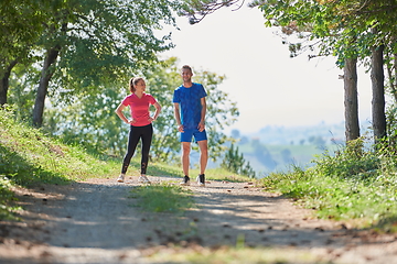 Image showing couple enjoying in a healthy lifestyle while jogging on a country road