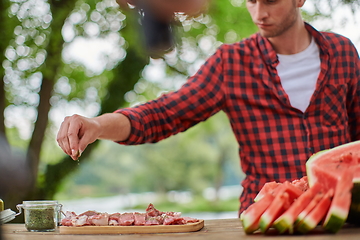 Image showing man putting spices on raw meat for barbecue