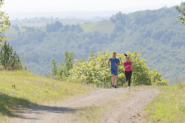 Image showing couple enjoying in a healthy lifestyle while jogging on a country road