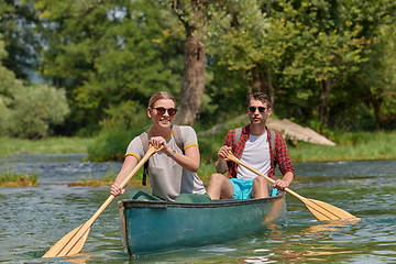 Image showing friends are canoeing in a wild river