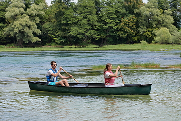 Image showing friends are canoeing in a wild river