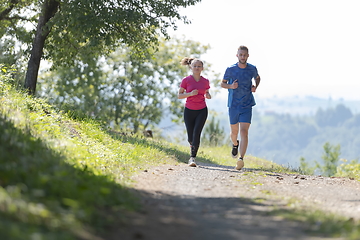 Image showing couple enjoying in a healthy lifestyle while jogging on a country road