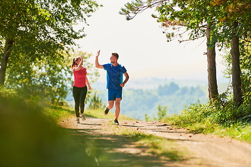 Image showing couple enjoying in a healthy lifestyle while jogging on a country road