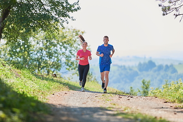 Image showing couple enjoying in a healthy lifestyle while jogging on a country road