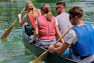 Image showing Group adventurous explorer friends are canoeing in a wild river