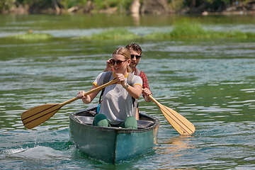 Image showing friends are canoeing in a wild river