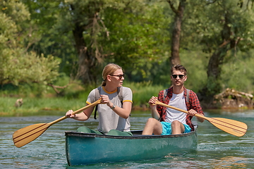 Image showing friends are canoeing in a wild river