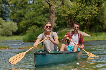 Image showing friends are canoeing in a wild river