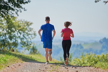 Image showing couple enjoying in a healthy lifestyle while jogging on a country road