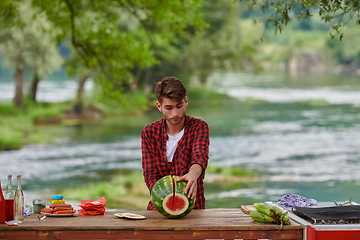 Image showing man cutting juicy watermelon during outdoor french dinner party