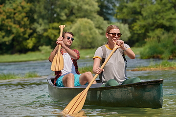 Image showing friends are canoeing in a wild river