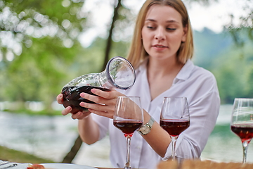 Image showing woman pouring red wine into glasses