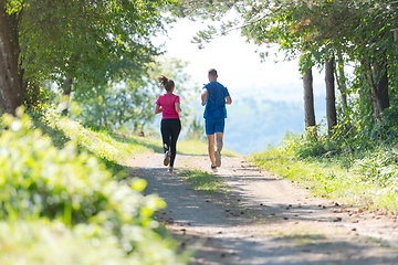 Image showing couple enjoying in a healthy lifestyle while jogging on a country road