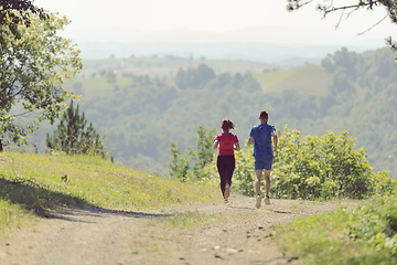 Image showing couple enjoying in a healthy lifestyle while jogging on a country road