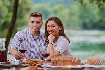 Image showing couple toasting red wine glass while having picnic french dinner party outdoor