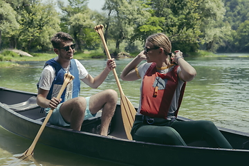 Image showing friends are canoeing in a wild river