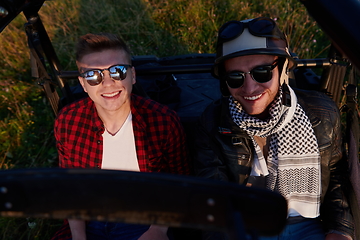 Image showing two young happy excited men enjoying beautiful sunny day while driving a off road buggy car