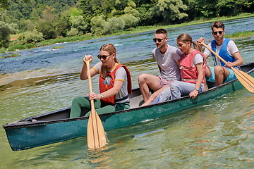 Image showing Group adventurous explorer friends are canoeing in a wild river