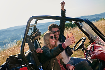 Image showing couple enjoying beautiful sunny day taking selfie picture while driving a off road buggy