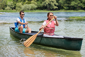 Image showing friends are canoeing in a wild river