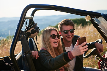 Image showing couple enjoying beautiful sunny day taking selfie picture while driving a off road buggy