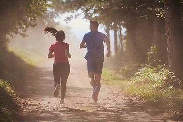 Image showing couple enjoying in a healthy lifestyle while jogging on a country road