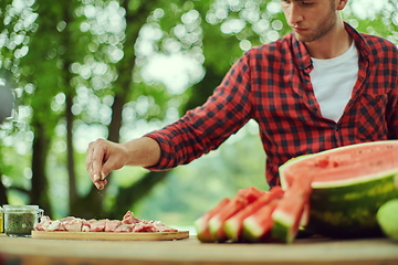 Image showing man putting spices on raw meat for barbecue