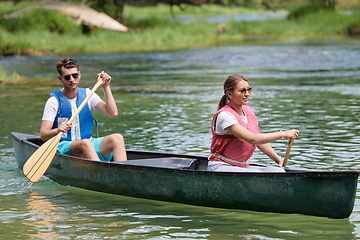 Image showing friends are canoeing in a wild river